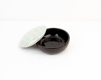 May include: A ceramic bowl with a lid. The bowl is brown and the lid is white with green stripes. The lid has the word "Italia" written on it.