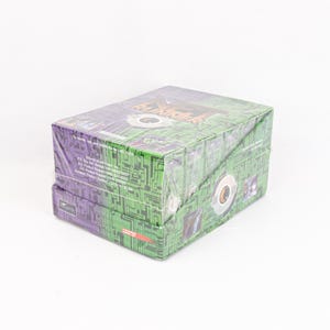 May include: Two stacked boxes wrapped in clear plastic. The boxes feature a green circuit board design on the sides and purple tops. The top of the box has the text "The Shadowlords".