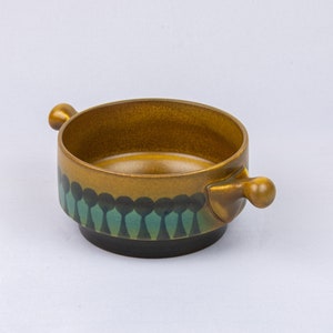 May include: A brown ceramic bowl with two handles. The bowl has a green and black geometric pattern around the rim.