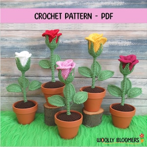Puede incluir: Patrón de crochet PDF para hacer cinco rosas amigurumi en diferentes colores: rojo, blanco, amarillo, rosa y burdeos. Cada rosa está en maceta en una maceta marrón y tiene hojas verdes.