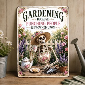 Könnte beinhalten: Ein rechteckiges Metallschild mit einem Skelett, das einen Strohhut und eine geblümte Schürze trägt und in einem Garten mit Teekanne, Teetasse und Keks sitzt. Der Text lautet: GARDENING BECAUSE PUNCHING PEOPLE IS FROWNED UPON. Umgeben von Rosen.