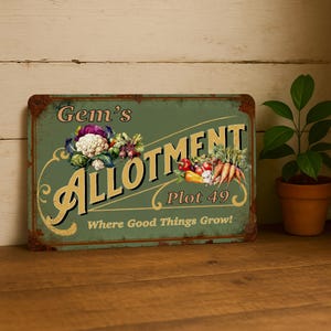 Puede incluir: Un letrero metálico de estilo vintage con fondo verde y las palabras "Gem's Allotment Plot 49" en letras doradas. El letrero presenta ilustraciones de verduras frescas y la frase "Where Good Things Grow!"
