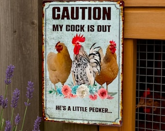 Peut inclure: Panneau métallique rectangulaire avec une finition vieillie, portant l'inscription "CAUTION MY COCK IS OUT" en marron foncé. En dessous, des illustrations de trois poulets et la phrase "HE'S A LITTLE PECKER..." dans un style rustique.