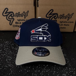 May include: A navy blue and grey baseball cap with a white and red logo that says "SOX". The cap has an adjustable strap in the back.