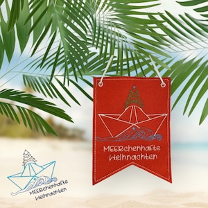 May include: A red felt Christmas ornament with a white paper boat and a green Christmas tree inside. The ornament has a white string for hanging and the text "Meerchenhafte Weihnachten" in white.