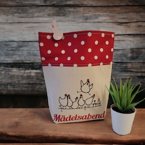 May include: Red and white polka dot fabric tote bag with a white embroidered design of chickens drinking wine. The bag has the text "Mädelsabend" embroidered on the bottom.