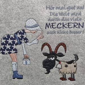 Könnte beinhalten: Eine Frau in einem blau-weißen Kleid mit Sternenmuster zeigt auf eine Ziege mit einer Glocke um den Hals. Der Text auf dem Bild lautet "Hör mal gut zu! Die Welt wird durch das viele MECKERN auch nicht besser!"