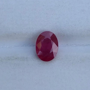 Könnte beinhalten: Ein leuchtend roter ovaler Edelstein mit Facettenschliff.