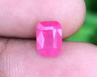 May include: A pink gemstone with a rectangular shape and a faceted cut.