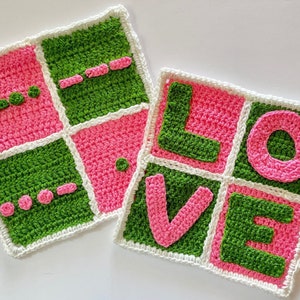 Può includere: Due quadrati all'uncinetto, uno con sfondo rosa e quadrati verdi, l'altro con sfondo verde e quadrati rosa. I quadrati sono uniti per formare la parola "LOVE" in filato rosa e verde.