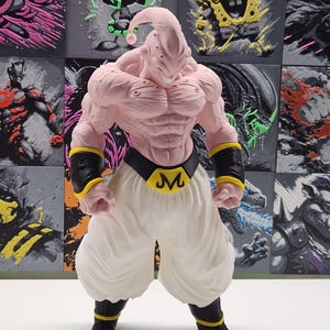 May include: A pink figurine of the character Majin Buu from Dragon Ball Z, with white pants, a black belt with a yellow "M", and black and yellow wristbands and boots. The background features various pop culture character art.