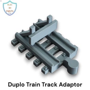 Può includere: Un adattatore per binari del treno Duplo grigio. Il pezzo di plastica ha una forma rettangolare con binari paralleli e strutture di supporto. Il testo "Duplo Train Track Adaptor" è stampato sotto.