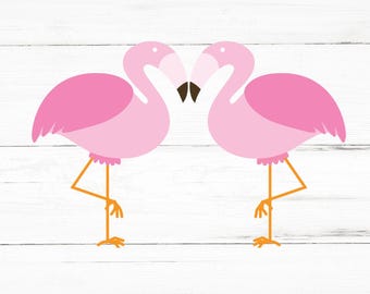 May include: Two pink flamingos facing each other with their beaks touching. The flamingos are standing on a white wooden background.