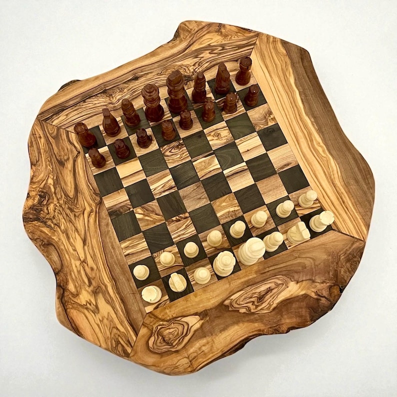 Puede incluir: Un juego de ajedrez de madera con un borde de borde vivo. El tablero presenta cuadrados oscuros y claros alternos, con piezas de ajedrez en su lugar. Las piezas son marrones y blancas. El tablero es de madera de olivo.