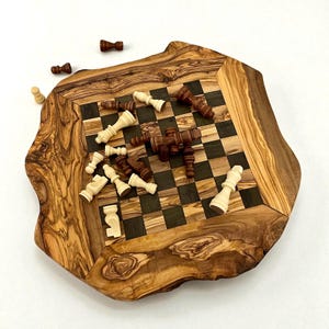 Puede incluir: Un juego de ajedrez de madera con borde natural. El tablero presenta un patr&oacute;n de cuadros en tonos de madera oscuros y claros. Las piezas de ajedrez est&aacute;n esparcidas por el tablero, algunas claras y otras de color marr&oacute;n oscuro.