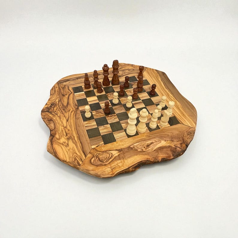 Puede incluir: Un juego de ajedrez de madera con un tablero de madera de olivo de borde vivo. El tablero presenta una superficie de juego a cuadros con cuadrados oscuros y claros. Las piezas de ajedrez son de dos colores, marr&oacute;n oscuro y beige claro.