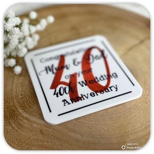 May include: White square coaster with black border and text "Congratulations Mum & Dad on your 40th Wedding Anniversary". The number 40 is in red glitter.