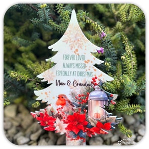 May include: A white wooden Christmas tree ornament with a red robin, poinsettia flowers, and a lantern. The ornament has the text "Forever Loved Always Missed Especially at Christmas Nan & Grandad".