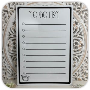 May include: A white rectangular To Do List board with a black border. The words "TO DO LIST" are at the top. There are 10 horizontal lines with circles to the left. A small notebook and pencil graphic is in the bottom left corner.