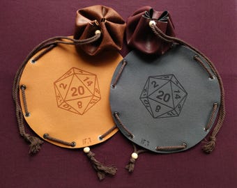 May include: Two leather dice bags, one tan and one gray, with a D20 die design. Each bag has a drawstring closure and a tassel. The tan bag has a brown leather pouch, and the gray bag has a dark brown leather pouch.