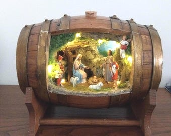 Belén napolitano en un barril de madera, un belén rústico e iluminado hecho a mano.