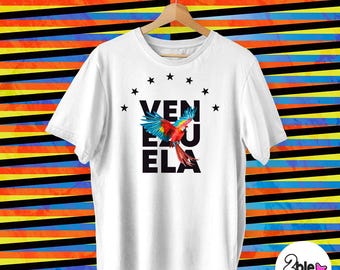 May include: White t-shirt with a black graphic of a parrot flying with the word "VENEZUELA" in black letters and stars around the word.