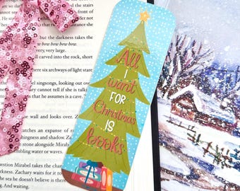 May include: A Christmas-themed bookmark with a green Christmas tree design and the text "All I want for Christmas is books." The bookmark has a blue background with white snowflakes and a gold star on top.