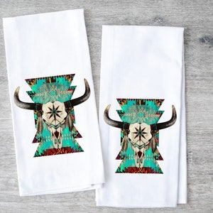 May include: Two white kitchen towels with a turquoise, red, and black geometric pattern and a white bull skull with feathers in the center.