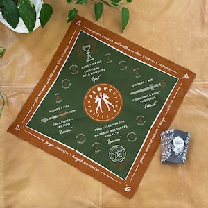 May include: Square bandana with a brown border and a green center featuring tarot-inspired illustrations and text. The design includes symbols, phrases like "Cups Water Emotions Relationships", and the words "Major Arcana" and "Minor Arcana".