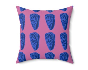 May include: A pink cushion with a repeating pattern of blue seashells. The seashells are stylised and have a textured appearance.