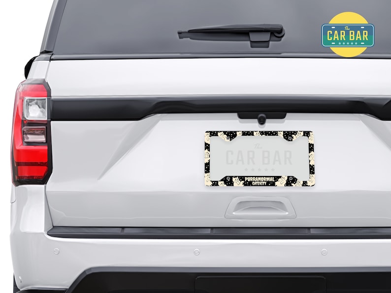 Puede incluir: Marco de matr&iacute;cula negro y blanco con un dise&ntilde;o de gato y el texto "The Car Bar" y "Purrranormal Activity".