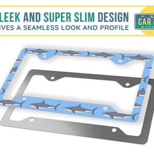 May include: A blue and silver license plate frame with a shark pattern. The frame is made of metal and has a sleek and slim design. The text "The Car Bar" is printed on the frame.