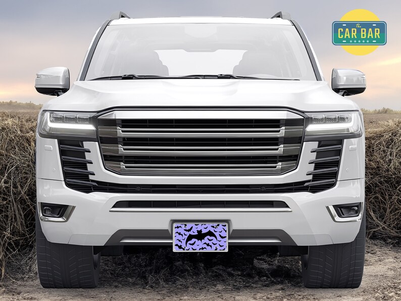 May include: A white SUV with a black grille and a license plate that says "The Car Bar" with a purple background and a black bat design.