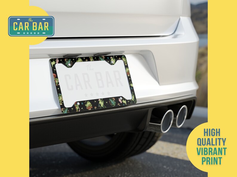 May include: A black license plate frame with a green and black floral design. The frame has the text "The Car Bar" printed on it.