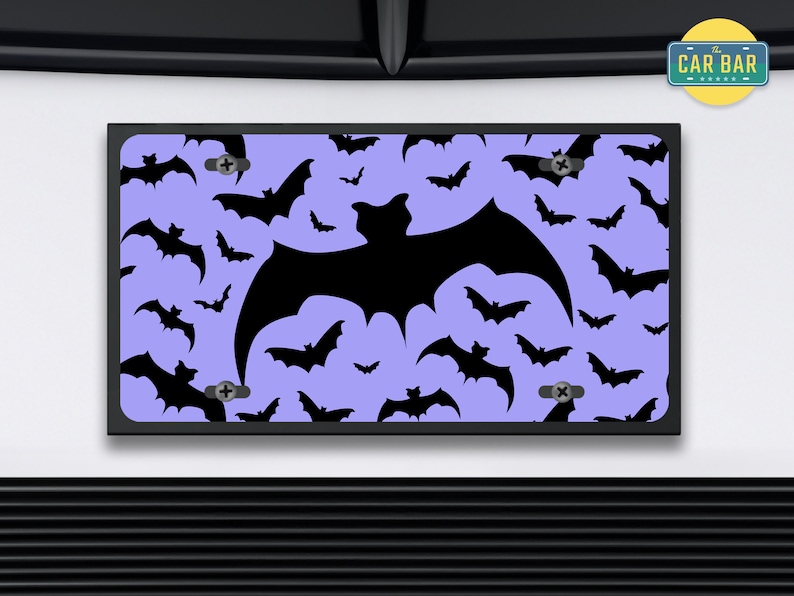 May include: A purple license plate with a black bat silhouette pattern. The bat silhouette is repeated throughout the plate. The plate has two screw holes on the top and bottom. The text "The Car Bar" is visible in the upper right corner of the image.