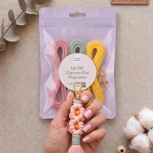 Puede incluir: Un kit de llavero macramé DIY con cordones rosas, verdes y amarillos. El kit incluye un cierre dorado y un llavero terminado con un diseño de flores y una borla rosa. El embalaje tiene el texto "Kit DIY Llavero Flor Macrame".