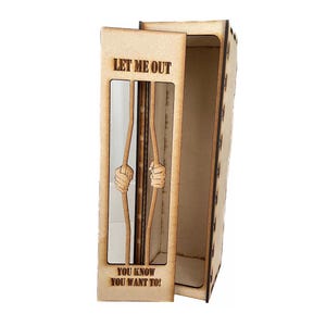 K&ouml;nnte beinhalten: Eine Holzkiste mit einem Gef&auml;ngniszellen-Design. Die Kiste ist ge&ouml;ffnet und der Text "Let me out" und "You know you want to!" ist sichtbar.