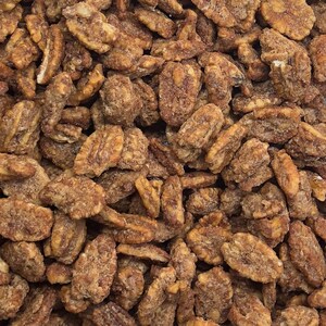 Peut inclure: Une image en gros plan d'un grand tas de moitiés de noix de pécan enrobées d'un glaçage brun et sucré. Les noix de pécan sont de couleur brun clair et ont une texture légèrement croquante.