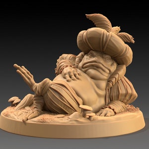May include: A tan-colored sculpture of a frog in Renaissance attire, including a hat with a feather. The frog is reclining on a small, round base with mushrooms and foliage. The sculpture has detailed textures and a whimsical design.