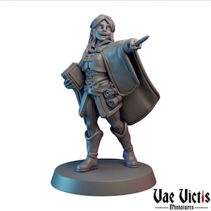 May include: A gray painted miniature figurine of a female character wearing a long cloak and holding a book and a staff. The character is smiling and has a determined expression. The miniature is standing on a round base.