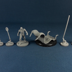 May include: A set of six miniature figurines, including a knight, a shield, a spear, a sword, a spoon, and a rolled-up cloth. The figurines are all gray and are set on a gray surface.