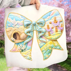 May include: A decorative bow-shaped artwork with a religious theme. The artwork features a light blue bow with gold trim, a dove, an empty tomb, and three crosses. The background has a pastel color scheme with flowers and a sky.