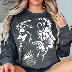 May include: Dark gray sweatshirt featuring a white graphic of Jesus wearing a crown of thorns, a lion, and a lamb. The word "ORIGINAL" is printed on a circular stamp. The sweatshirt is a comfortable, casual style.