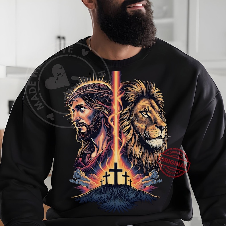 May include: Black sweatshirt featuring a graphic design with Jesus on one side and a lion on the other, separated by a vertical beam of light. The design includes three crosses on a hill, with the words "MADE WITH LOVE" and "ORIGINAL" in a circular stamp.