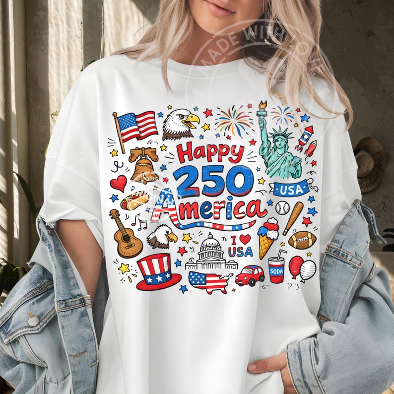 May include: White t-shirt with a colorful graphic celebrating America's 250th anniversary. The design includes an American flag, an eagle, the Statue of Liberty, fireworks, and other patriotic symbols.