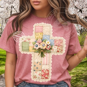 May include: A pink t-shirt featuring a cross design. The cross is made of patchwork squares in various colors and patterns, with a bouquet of flowers at the center. The cross is trimmed with a lace border. The shirt has a round neckline and short sleeves.