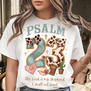 May include: White t-shirt with a graphic design featuring the word "PSALM" above the number "23". The design includes a bow, a heart with the word "Faith", a cowboy hat, a Bible, and a cactus. The text "The Lord is my Shepherd I shall not want" is below.