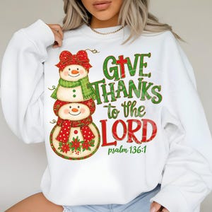 May include: White sweatshirt featuring a snowman design with a red bow, green scarf, and red polka dot scarf. The text "GIVE THANKS to the LORD" is printed in green and red, with "psalm 136:1" below.
