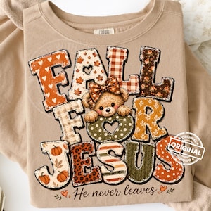 May include: A tan crewneck sweatshirt featuring a graphic with the text FALL FOR JESUS and He never leaves. The design includes a teddy bear with a bow, pumpkins, and various autumn-themed patterns like plaid, leaves, and polka dots in orange, brown, and green.