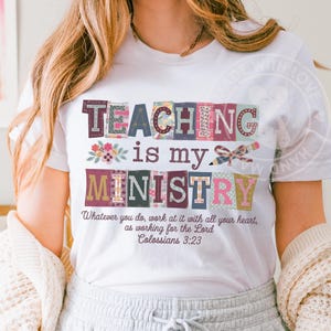 May include: White t-shirt with the text "TEACHING is my MINISTRY" in colorful block letters. The shirt also features a floral design and a pencil with a bow. The quote "Whatever you do, work at it with all your heart, as working for the Lord Colossians 3:23" is also printed on the shirt.